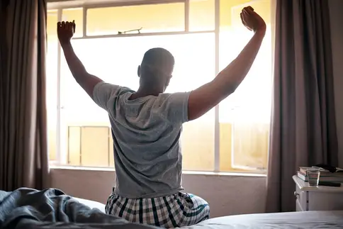 photo of man stretching on bed in morning